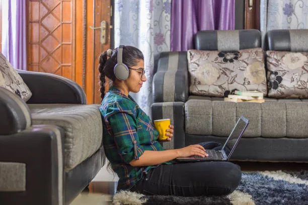 a teenage girl is doing online study from home by using a laptop and headphone
