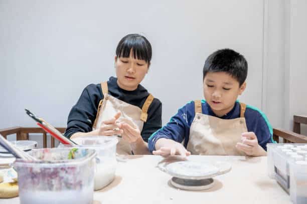 Mother and boy make ceramics together on the table at home.